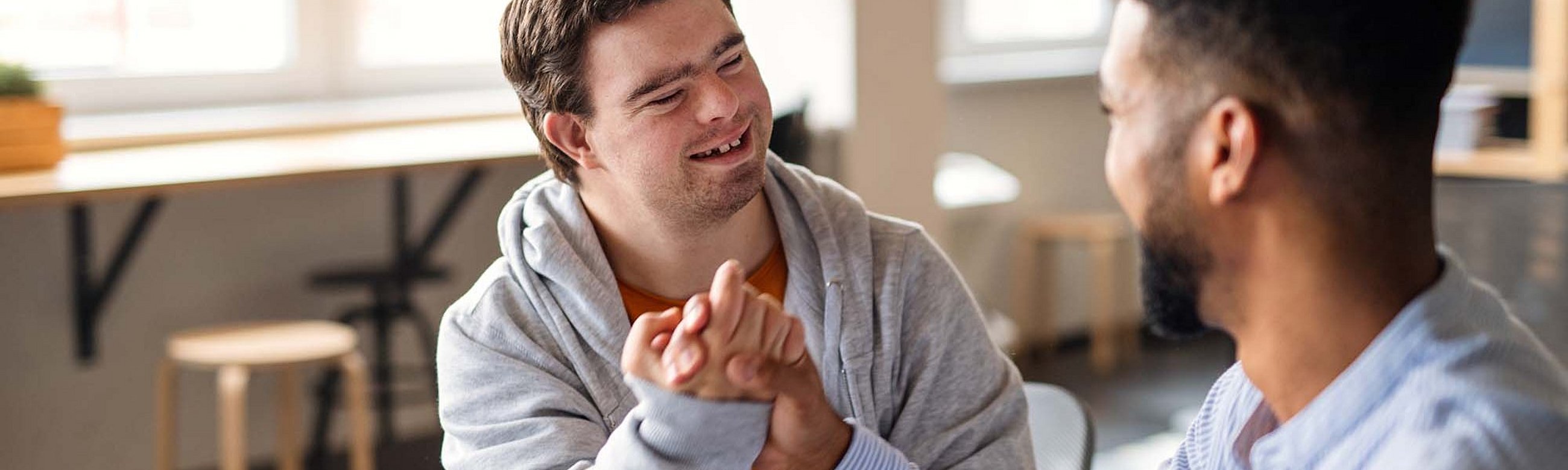 Zwei Männer machen einen Bro-Handschlag, einer hat Down Syndrom